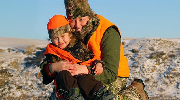 Close up of Mother with her child in the wilderness wearing blaze orange camouflage